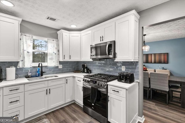 kitchen featuring appliances with stainless steel finishes, a textured ceiling, dark hardwood / wood-style floors, and white cabinets