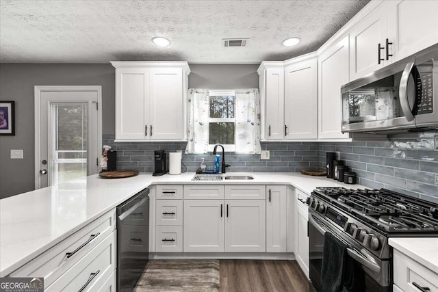 kitchen with sink, decorative backsplash, appliances with stainless steel finishes, white cabinets, and dark hardwood / wood-style flooring