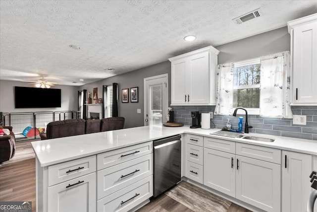 kitchen featuring dark wood-type flooring, sink, white cabinets, dishwasher, and kitchen peninsula