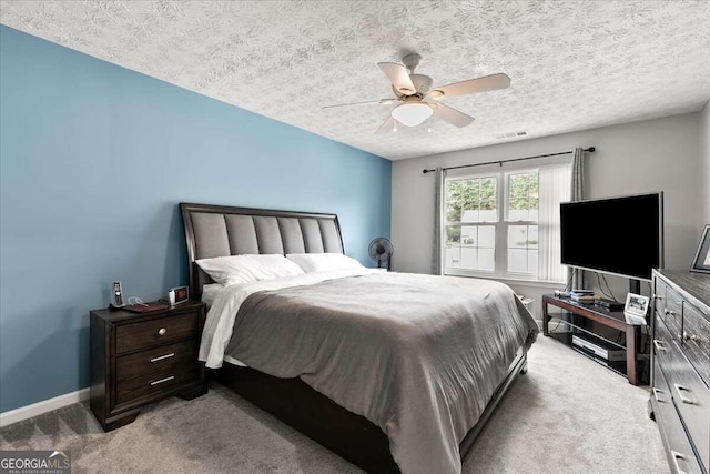 carpeted bedroom featuring ceiling fan and a textured ceiling