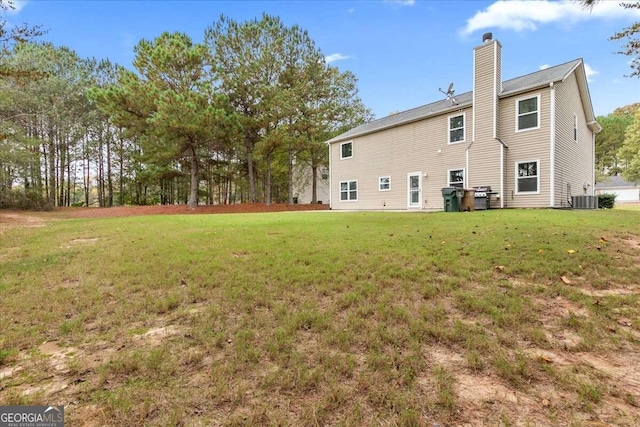 back of property with central AC unit and a yard