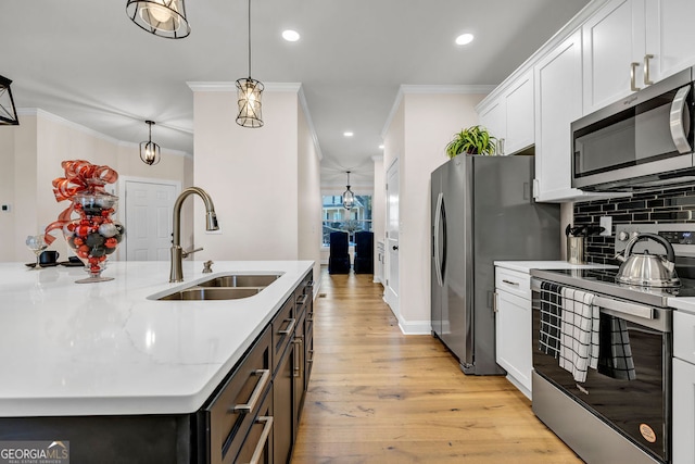 kitchen with sink, light hardwood / wood-style flooring, appliances with stainless steel finishes, decorative light fixtures, and white cabinetry