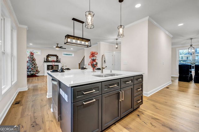 kitchen with a kitchen island with sink, sink, ceiling fan, decorative light fixtures, and light hardwood / wood-style floors