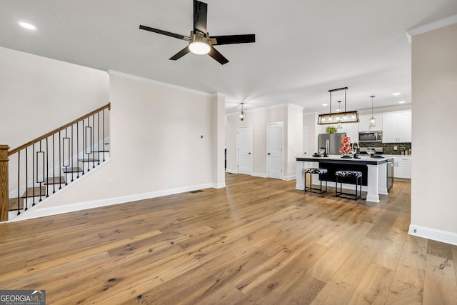 living room with ceiling fan, light hardwood / wood-style flooring, and ornamental molding