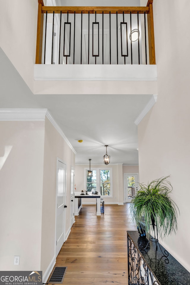 foyer entrance with crown molding, hardwood / wood-style floors, and an inviting chandelier