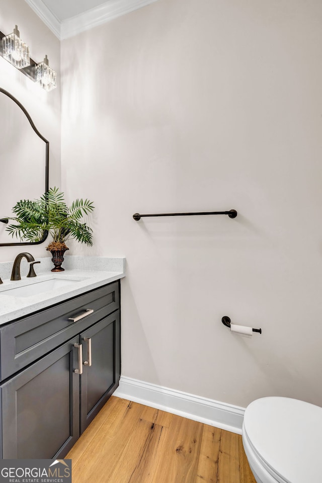 bathroom featuring wood-type flooring, vanity, toilet, and ornamental molding