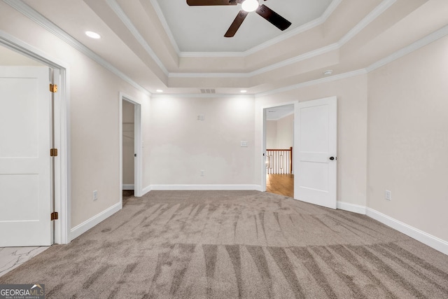 carpeted spare room with a tray ceiling, ceiling fan, and ornamental molding