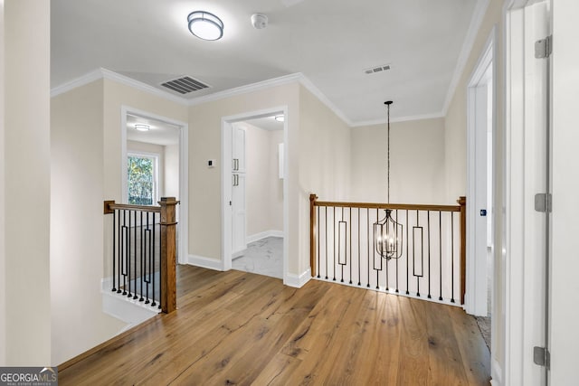 hallway featuring a chandelier, wood-type flooring, and ornamental molding