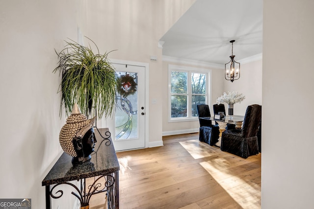 entryway featuring crown molding, a notable chandelier, and light wood-type flooring