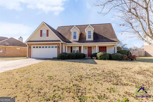 view of front of property featuring a porch, a front lawn, and a garage