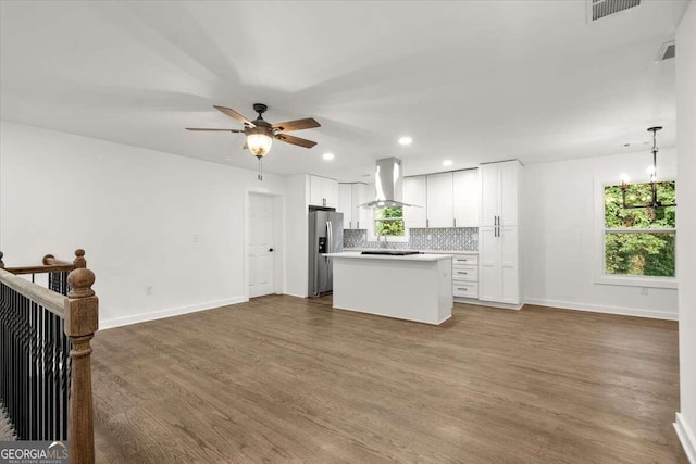 kitchen with white cabinetry, wall chimney range hood, stainless steel fridge with ice dispenser, and a kitchen island