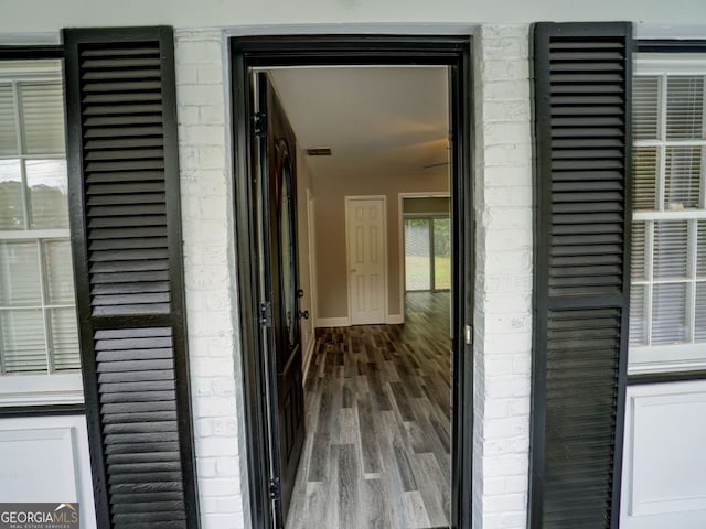 corridor featuring a wealth of natural light, wood-type flooring, and vaulted ceiling