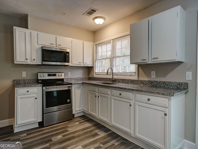 kitchen with appliances with stainless steel finishes, a textured ceiling, dark hardwood / wood-style flooring, sink, and white cabinets