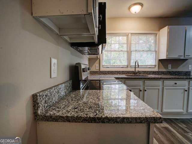 kitchen with white cabinets, range, sink, dark hardwood / wood-style floors, and dark stone countertops