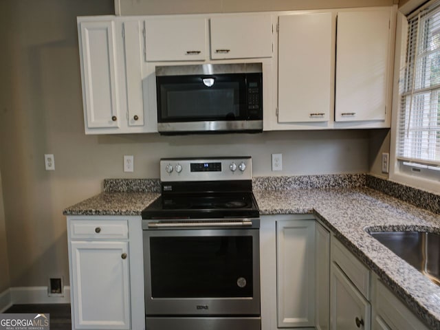 kitchen featuring white cabinets, a healthy amount of sunlight, light stone counters, and appliances with stainless steel finishes