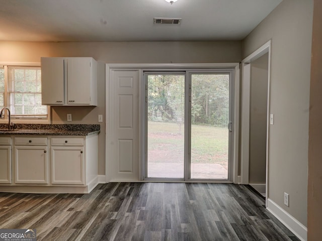 kitchen with dark stone counters, sink, dark hardwood / wood-style floors, and white cabinets