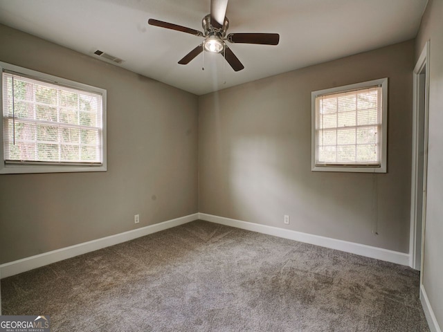 carpeted spare room featuring a wealth of natural light and ceiling fan