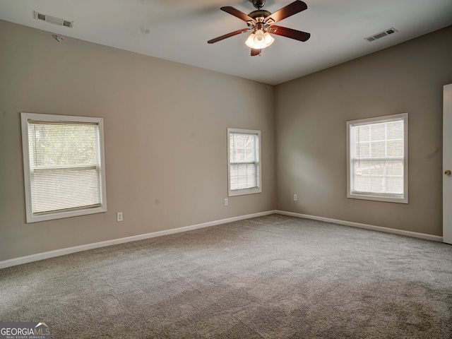 spare room with ceiling fan, plenty of natural light, and carpet