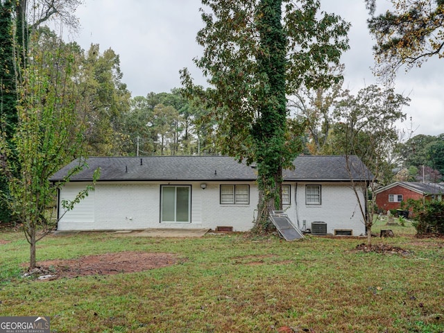 back of property with central AC unit and a lawn