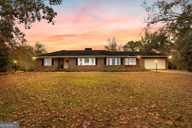 single story home featuring a garage and a lawn