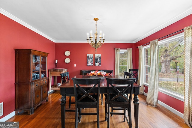 dining area with ornamental molding, plenty of natural light, hardwood / wood-style flooring, and a chandelier