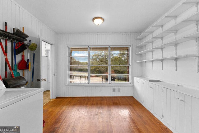 washroom with washer / clothes dryer, wood walls, and light hardwood / wood-style floors