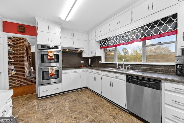 kitchen with ornamental molding, stainless steel appliances, sink, white cabinets, and brick wall