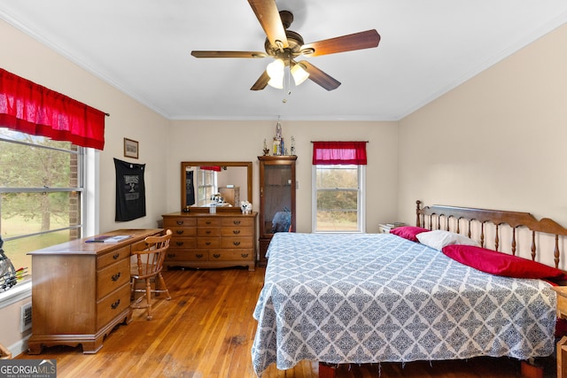 bedroom featuring ceiling fan, ornamental molding, and wood-type flooring