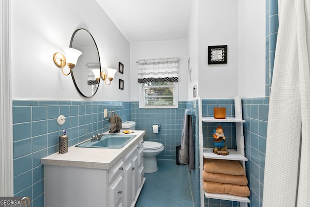 bathroom with toilet, vanity, tile walls, and tile patterned floors