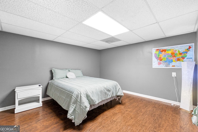 bedroom featuring a drop ceiling and hardwood / wood-style floors