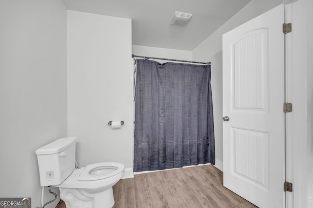 bathroom featuring walk in shower, hardwood / wood-style floors, and toilet