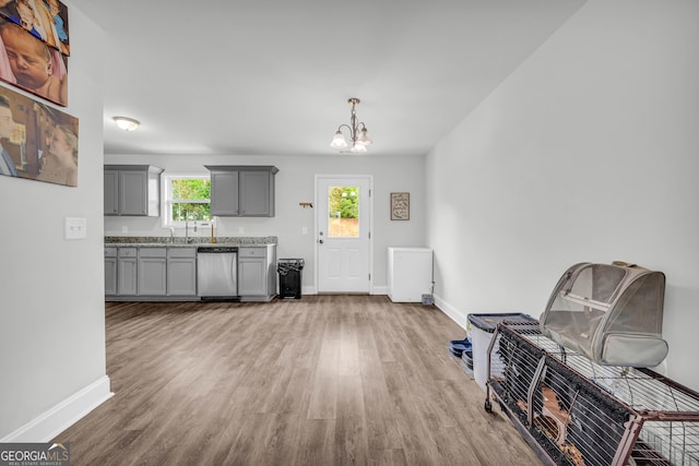 kitchen with an inviting chandelier, dishwasher, gray cabinets, pendant lighting, and light hardwood / wood-style flooring