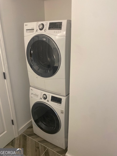 laundry area with dark wood-type flooring and stacked washing maching and dryer