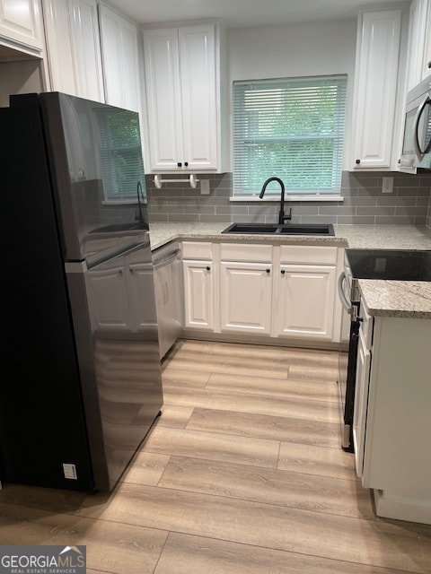 kitchen with white cabinetry, light hardwood / wood-style floors, appliances with stainless steel finishes, and sink