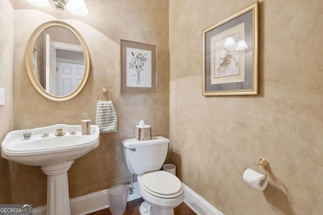 half bathroom with toilet and baseboards
