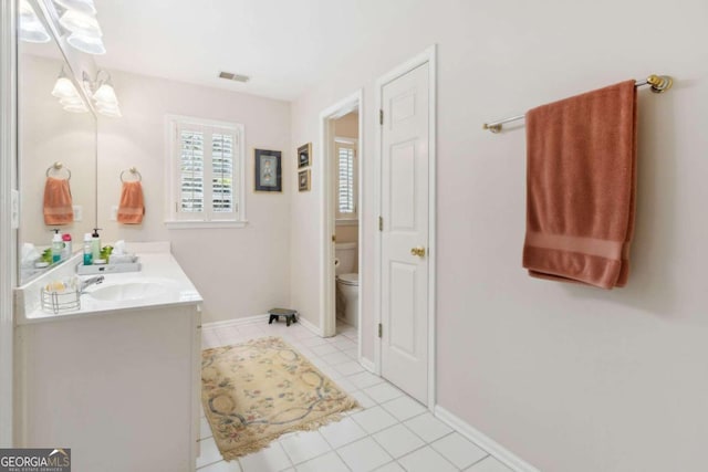 bathroom with vanity, baseboards, visible vents, tile patterned flooring, and toilet