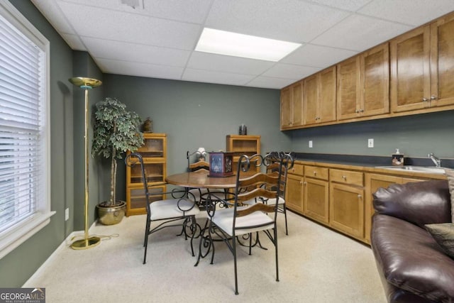 dining room with a drop ceiling, light colored carpet, and baseboards