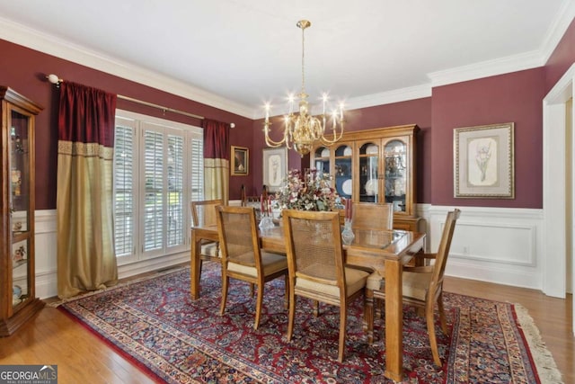 dining room with a chandelier, wainscoting, crown molding, and wood finished floors