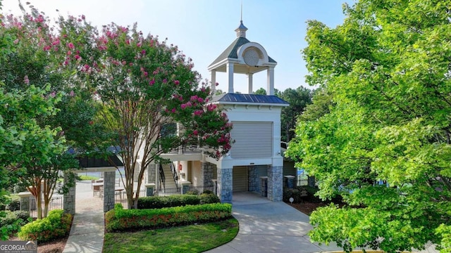 view of front facade with metal roof, stone siding, fence, and a standing seam roof