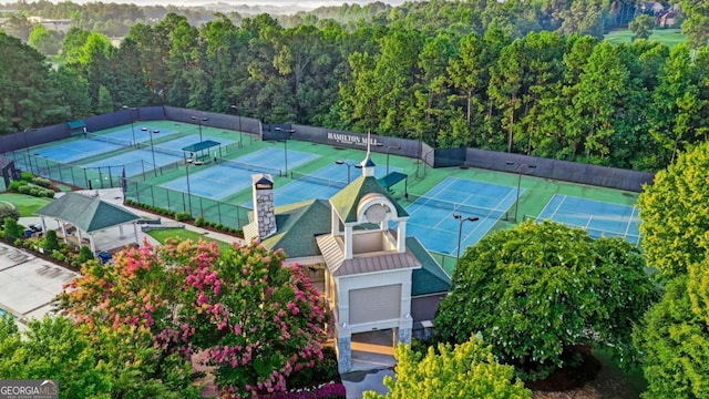 view of tennis court with fence and a forest view