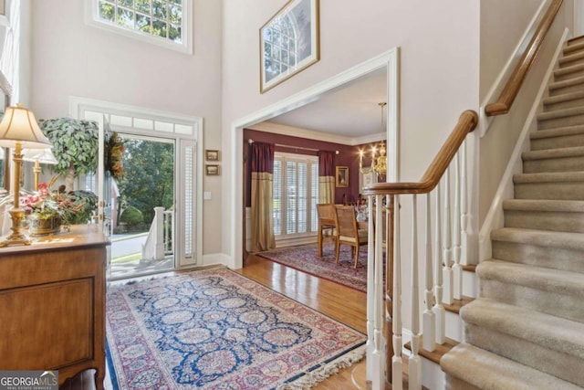 entrance foyer with a towering ceiling, stairs, baseboards, and wood finished floors