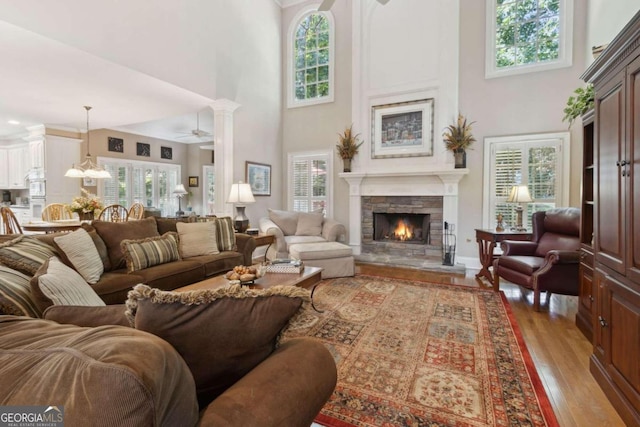 living area with plenty of natural light, a stone fireplace, and light wood-type flooring