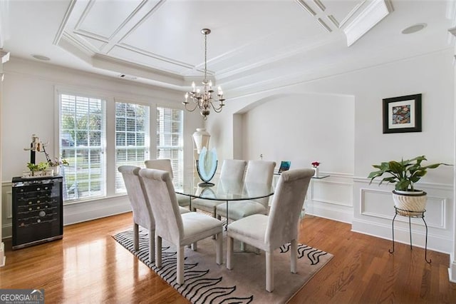 dining room featuring a chandelier, a tray ceiling, hardwood / wood-style floors, and ornamental molding