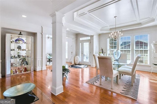 dining space featuring a tray ceiling, a wealth of natural light, wood-type flooring, and a notable chandelier