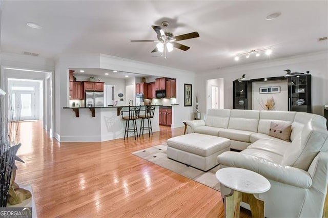 living room with ceiling fan, light wood-type flooring, and crown molding