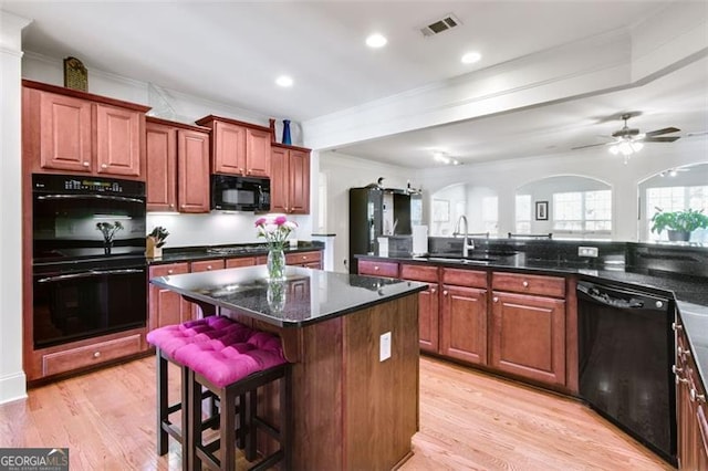 kitchen featuring black appliances, sink, ceiling fan, a kitchen island, and light wood-type flooring