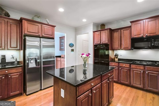 kitchen with crown molding, light hardwood / wood-style flooring, black appliances, and a center island