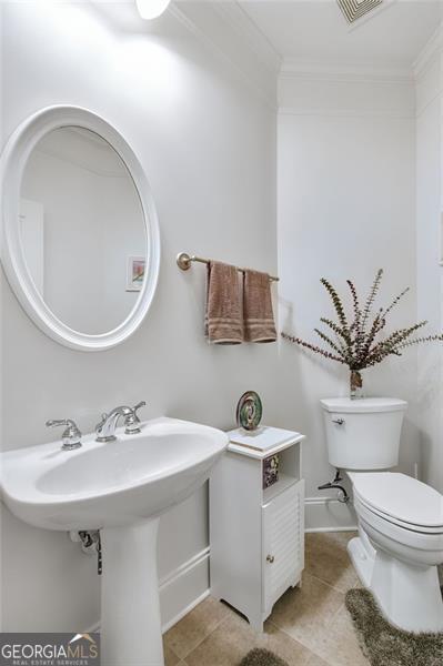 bathroom featuring tile patterned floors, toilet, and crown molding