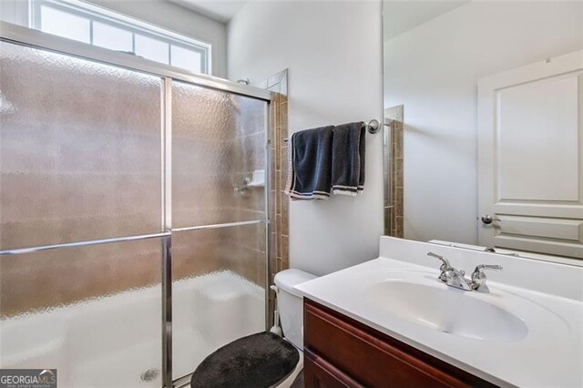 bathroom featuring walk in shower, vanity, and toilet