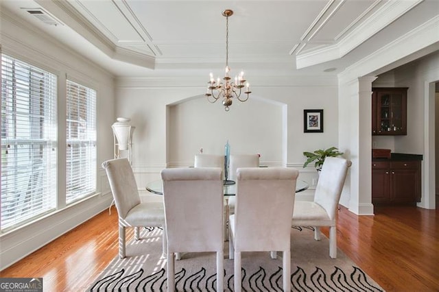 dining space with hardwood / wood-style flooring, an inviting chandelier, and ornamental molding